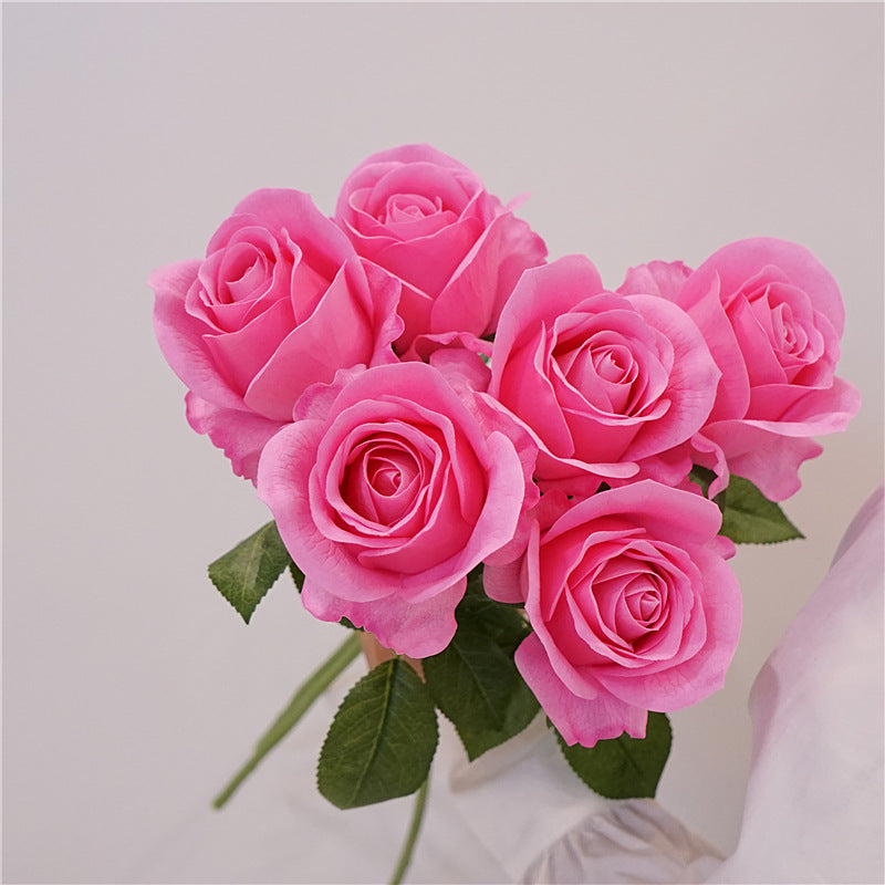 Bouquet of vibrant pink artificial roses with green leaves.