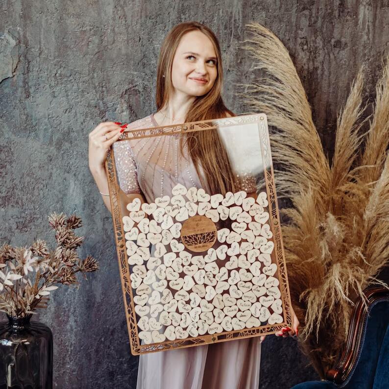 Woman holds wooden guestbook with heart-shaped notes for wedding.